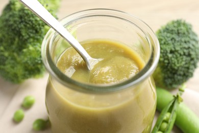 Photo of Baby food. Tasty puree in glass jar and ingredients on table, closeup
