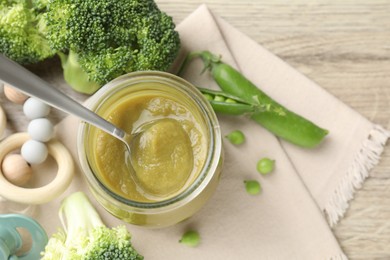 Photo of Baby food. Tasty puree in jar, ingredients, pacifier and teether on wooden table, flat lay