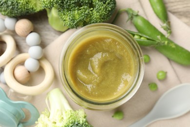 Photo of Baby food. Tasty puree in jar, ingredients, pacifier and teether on table, flat lay