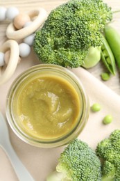 Photo of Baby food. Tasty puree in glass jar, ingredients and teether on table, flat lay
