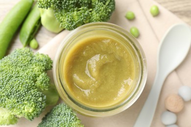Photo of Baby food. Tasty puree in glass jar, ingredients and spoon on table, flat lay