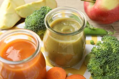 Photo of Baby food. Tasty puree in glass jars and ingredients on table, closeup