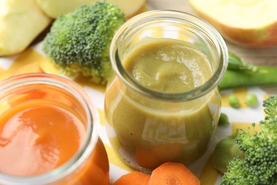 Photo of Baby food. Tasty puree in glass jars and ingredients on table, closeup