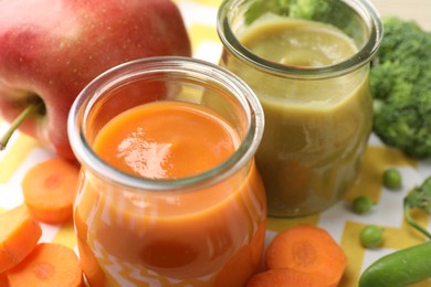Photo of Baby food. Tasty puree in glass jars and ingredients on table, closeup