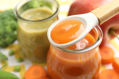Photo of Baby food. Tasty puree in spoon, glass jars and ingredients on table, closeup. Space for text