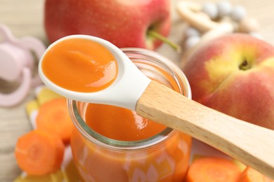 Photo of Baby food. Tasty puree in jar, ingredients and spoon on table, closeup