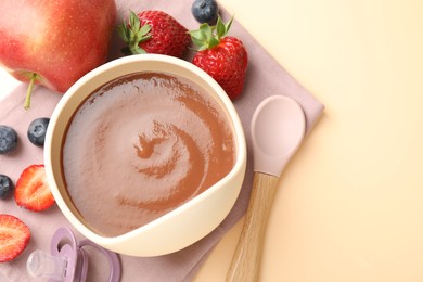 Photo of Baby food. Tasty puree in bowl, ingredients, pacifier and spoon on beige background, flat lay. Space for text
