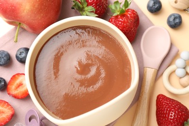 Photo of Baby food. Tasty puree in bowl, ingredients and spoon on beige background, flat lay