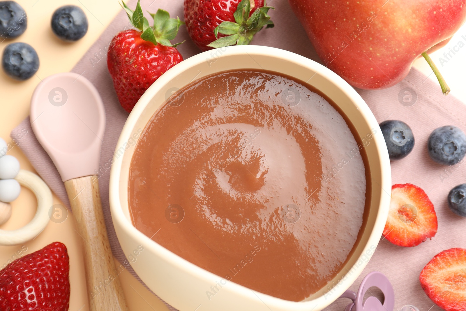 Baby food. Tasty puree in bowl, ingredients and spoon on beige background, flat lay Photo of Baby food. Tasty puree in bowl, ingredients and spoon on beige background, flat lay