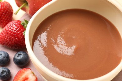 Photo of Baby food. Tasty puree in bowl and ingredients on table, closeup