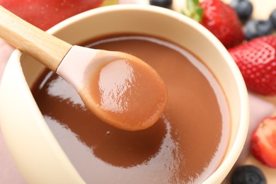 Photo of Baby food. Taking tasty puree with spoon at table, closeup