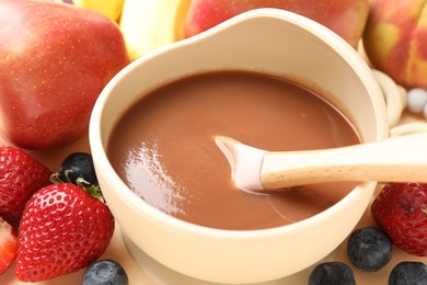 Photo of Baby food. Tasty puree in bowl and ingredients on table, closeup