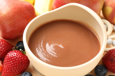 Photo of Baby food. Tasty puree in bowl and ingredients on table, closeup