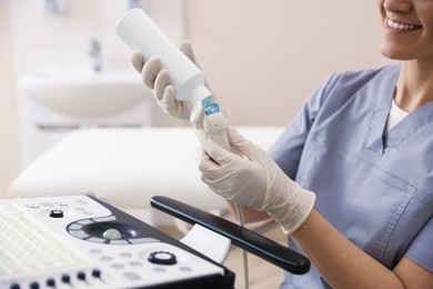 Photo of Sonographer applying gel on ultrasound transducer in clinic, closeup