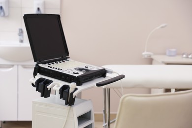 Photo of Modern ultrasound machine and examination bed in clinic