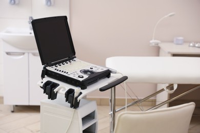Photo of Modern ultrasound machine and examination bed in clinic