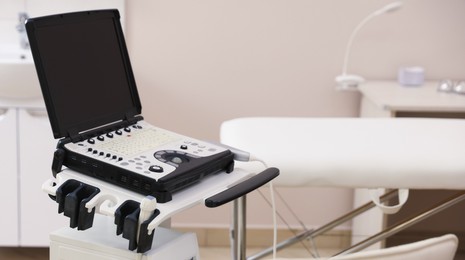 Photo of Modern ultrasound machine and examination bed in clinic