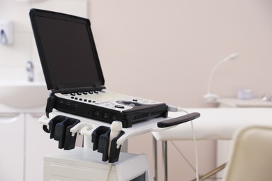 Photo of Modern ultrasound machine and examination bed in clinic