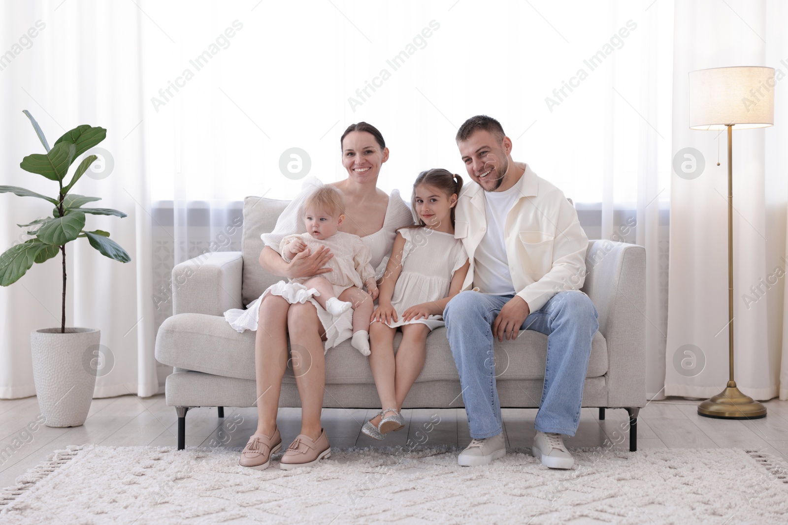 Happy parents and their kids together on sofa at home Photo of Happy parents and their kids together on sofa at home