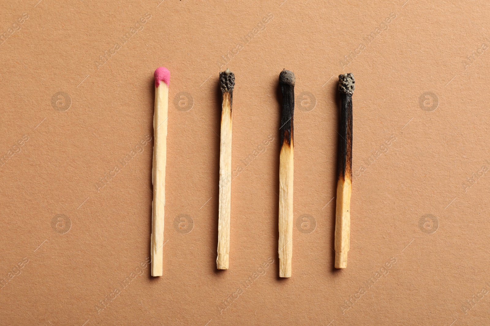 Burnt and whole matches on beige background, flat lay Photo of Burnt and whole matches on beige background, flat lay
