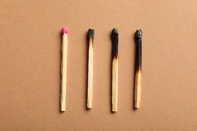 Photo of Burnt and whole matches on beige background, flat lay
