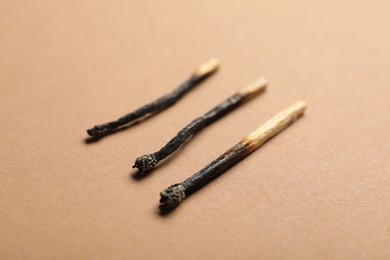 Photo of Burnt matches on beige background, closeup view