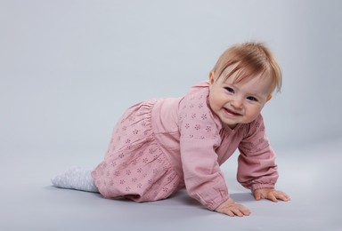 Photo of Cute little baby crawling on light grey background