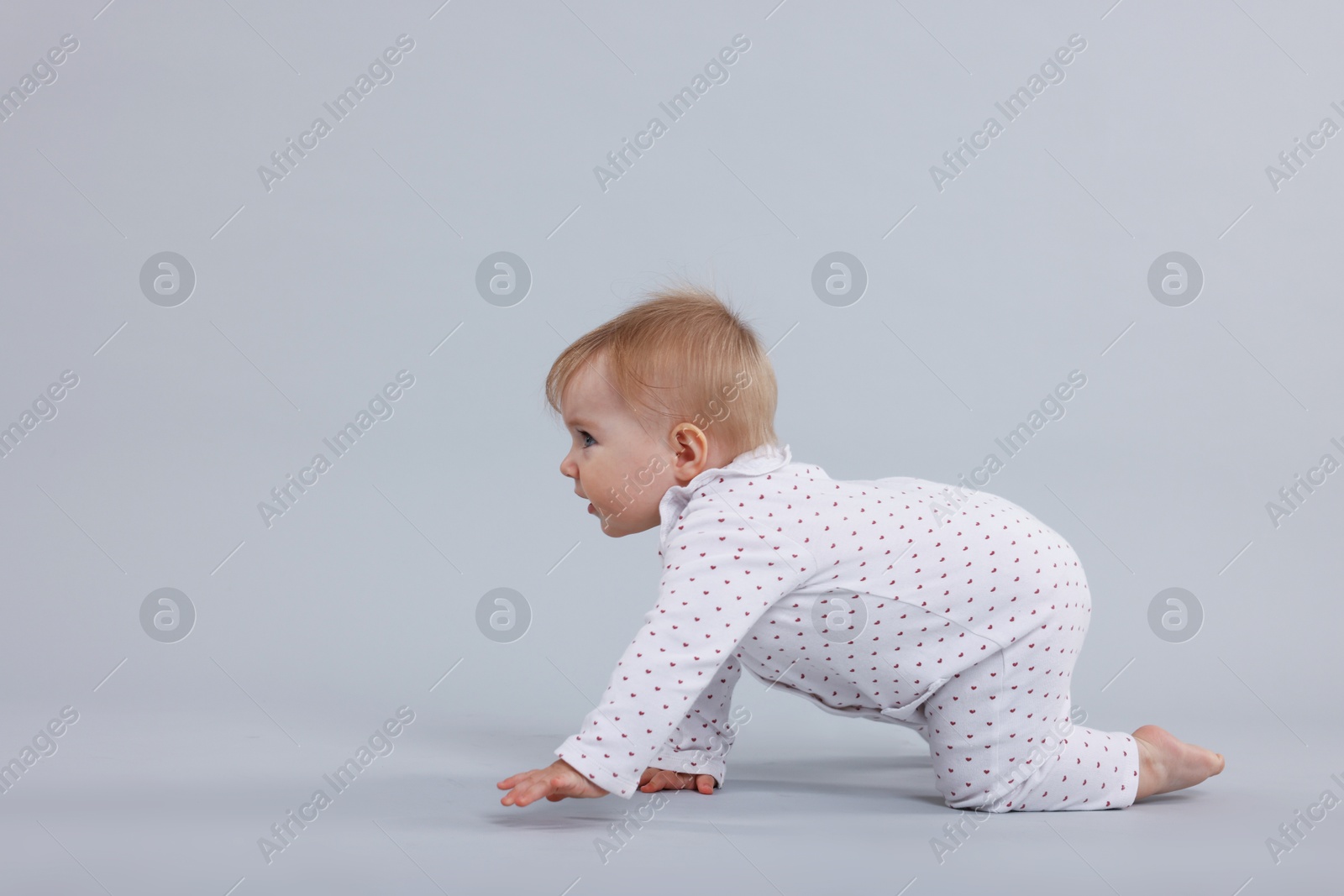 Cute little baby crawling on light grey background, space for text Photo of Cute little baby crawling on light grey background, space for text