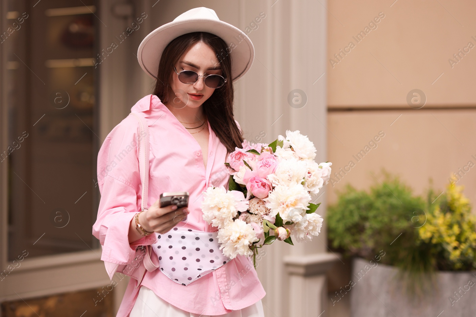 Stylish woman with bouquet of beautiful peonies and smartphone outdoors Photo of Stylish woman with bouquet of beautiful peonies and smartphone outdoors
