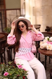 Photo of Stylish woman with beautiful peonies in outdoor cafe