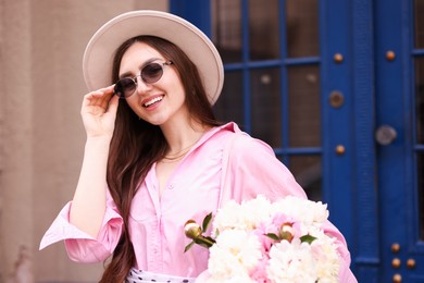 Photo of Stylish woman with beautiful peonies on city street