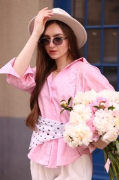 Photo of Stylish woman with beautiful peonies on city street