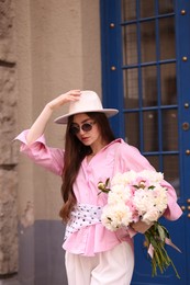 Photo of Stylish woman with beautiful peonies on city street