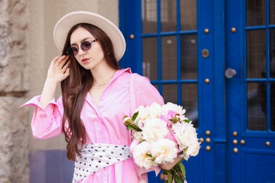 Photo of Stylish woman with beautiful peonies on city street