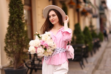 Photo of Stylish woman with beautiful peonies on city street