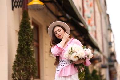 Photo of Stylish woman with beautiful peonies on city street