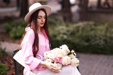 Photo of Beautiful woman with bouquet of peonies in park. Space for text