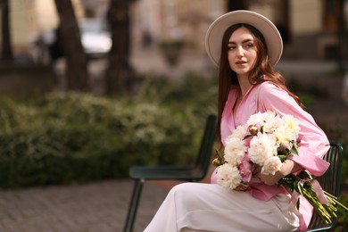 Photo of Beautiful woman with bouquet of peonies in park. Space for text