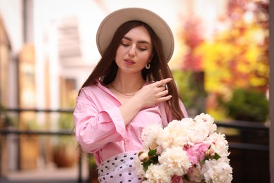 Photo of Stylish woman with beautiful peonies on city street