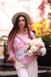 Photo of Stylish woman with beautiful peonies on city street