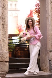Photo of Stylish woman with beautiful peonies on city street
