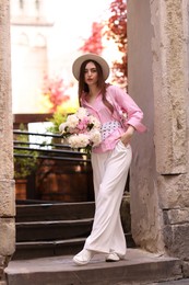 Photo of Stylish woman with beautiful peonies on city street