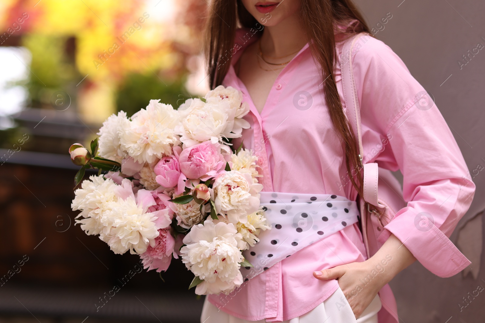 Stylish woman with beautiful peonies on city street, closeup Photo of Stylish woman with beautiful peonies on city street, closeup