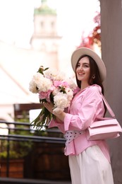 Photo of Stylish woman with beautiful peonies on city street