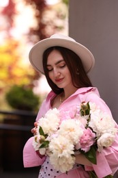 Photo of Stylish woman with beautiful peonies on city street