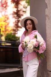 Photo of Stylish woman with beautiful peonies on city street