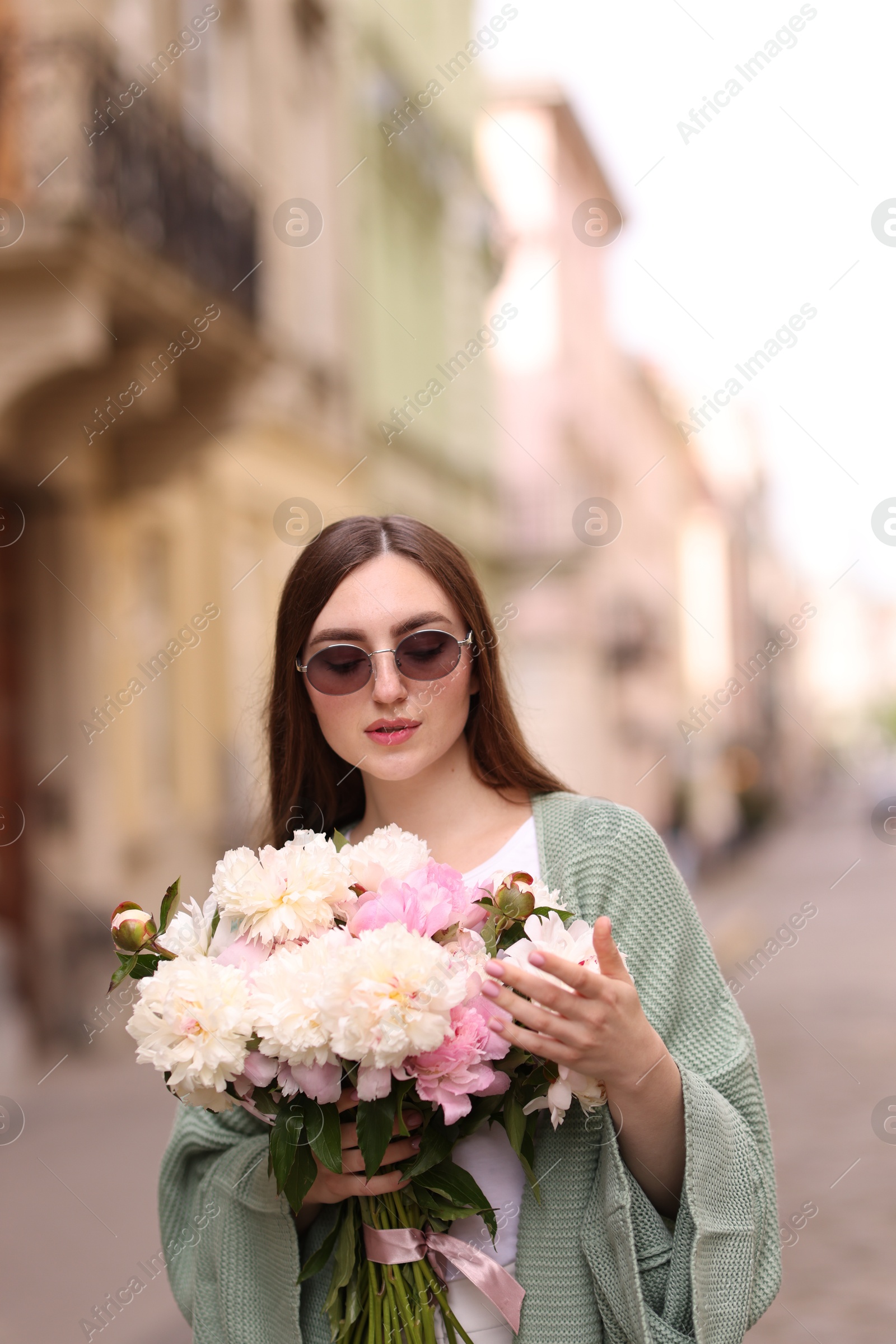 Charming woman with bouquet of beautiful peonies on city street Photo of Charming woman with bouquet of beautiful peonies on city street