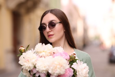 Photo of Charming woman with bouquet of beautiful peonies on city street