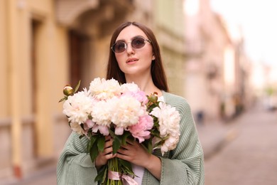 Photo of Charming woman with bouquet of beautiful peonies on city street