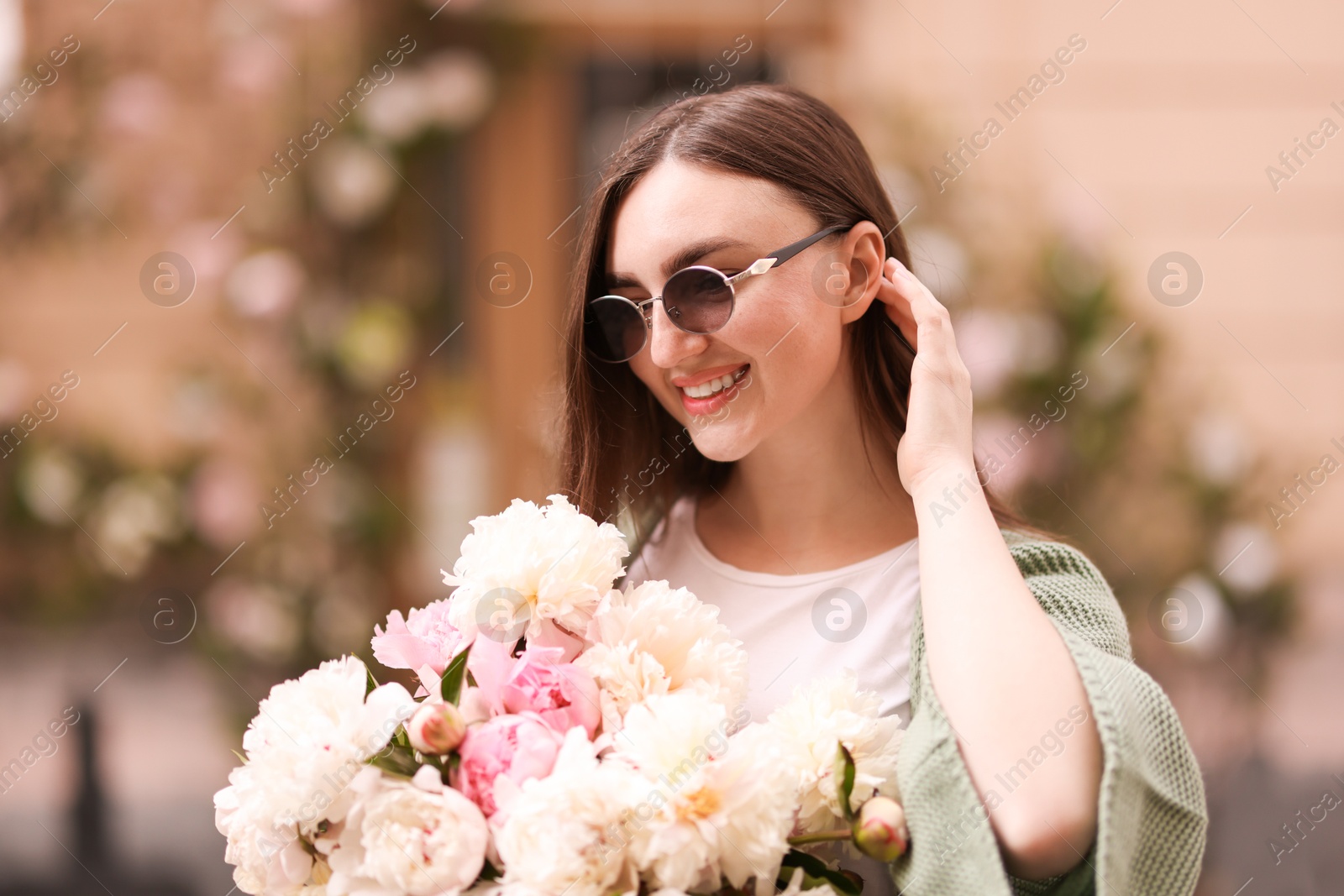 Charming woman with bouquet of beautiful peonies on city street Photo of Charming woman with bouquet of beautiful peonies on city street